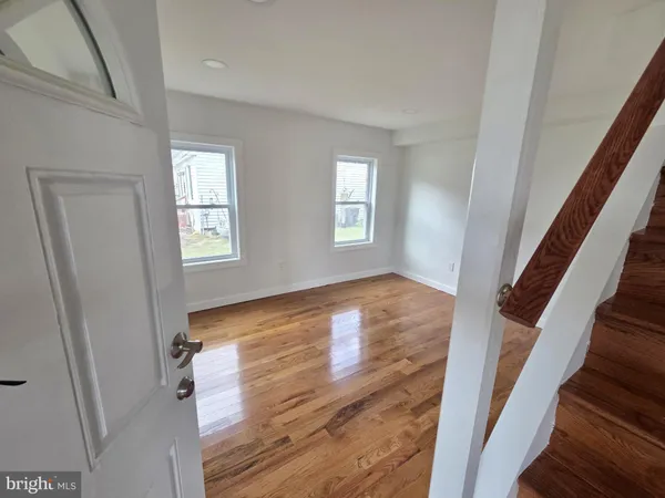 a view of an empty room with wooden floor and stairs