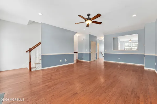 a view of an empty room with window and wooden floor