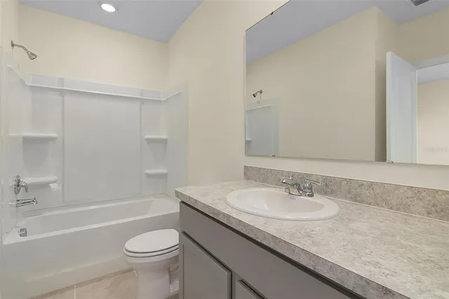 a bathroom with a granite countertop sink a toilet a mirror a bathtub and shower
