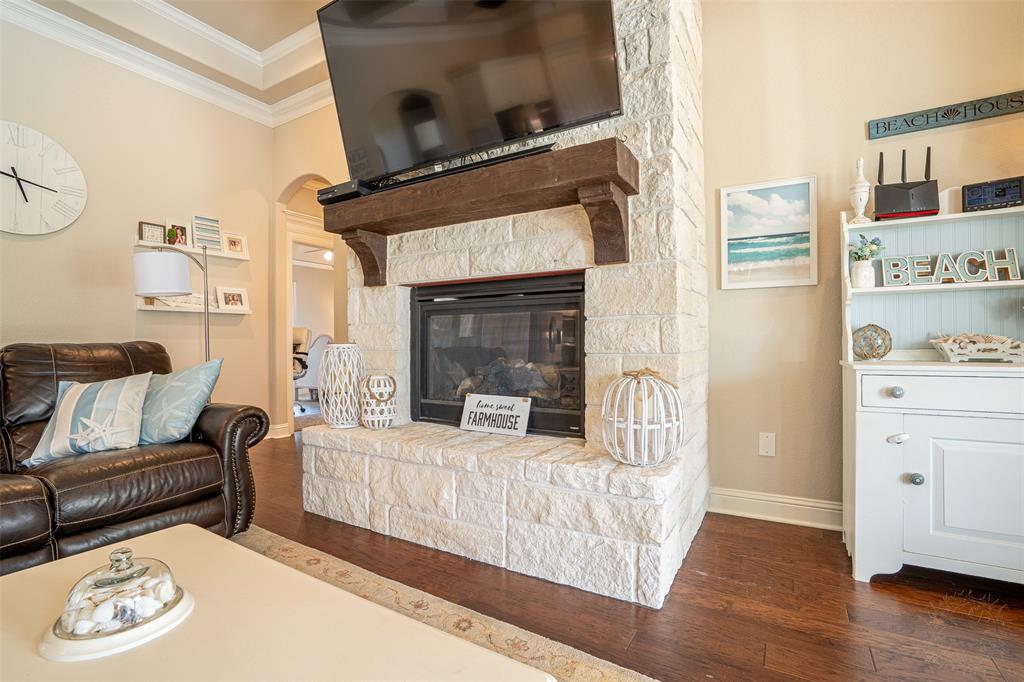 1920 Meander Road Granbury, TX 76049 - Photo 8 of 40 Stone-clad fireplace with a wood mantel, dark wood-finish flooring, and crown molding