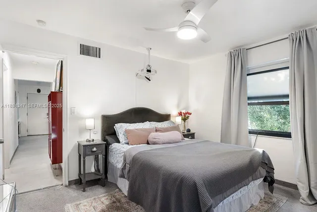 a bedroom with a large bed and a chandelier fan