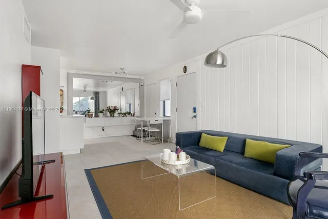 a living room with furniture and a refrigerator