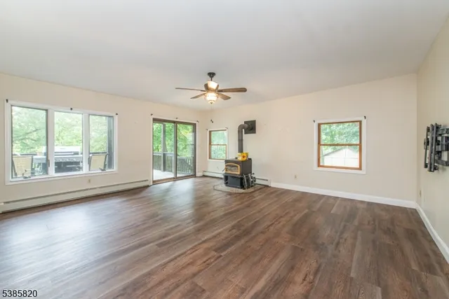 an empty room with wooden floor chandelier fan and windows