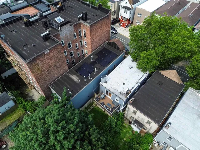 a view of a wooden house with a small yard plants and large tree