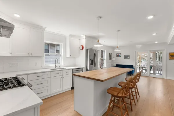 a kitchen with stainless steel appliances granite countertop a stove a sink a refrigerator a dining table and chairs with wooden floor