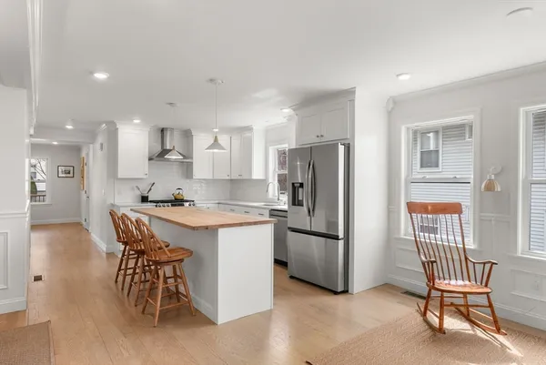 a kitchen with stainless steel appliances kitchen island a table chairs refrigerator and a sink