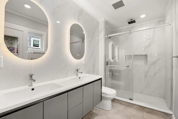 a bathroom with a double vanity sink toilet mirror and shower