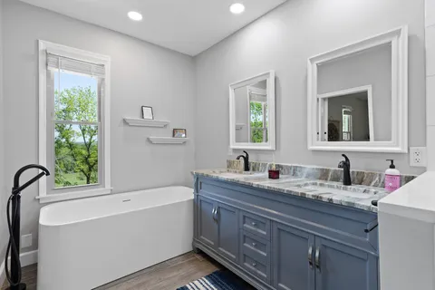 a bathroom with a granite countertop sink mirror and a bathtub