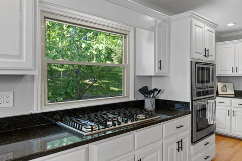 a kitchen with stainless steel appliances granite countertop a stove a sink dishwasher and cabinets with wooden floor