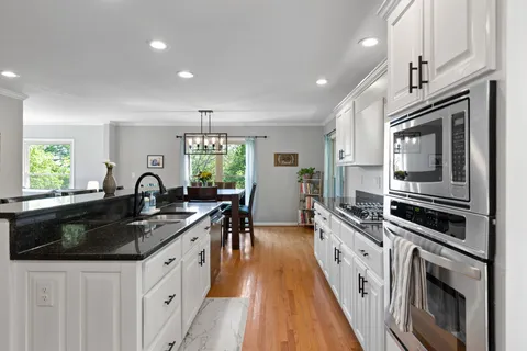 a kitchen with granite countertop a sink a stove refrigerator and cabinets