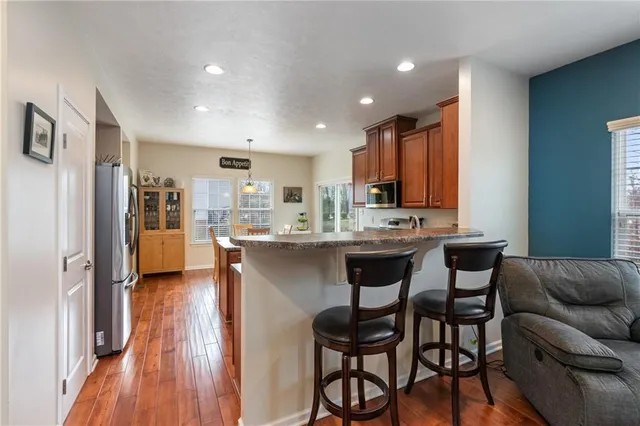 a living room with stainless steel appliances kitchen island granite countertop furniture and a wooden floor
