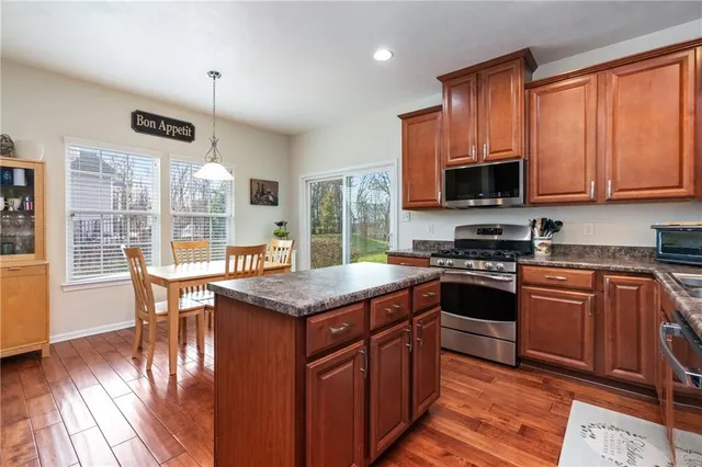 a kitchen with stainless steel appliances granite countertop a stove a sink and a microwave
