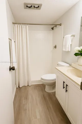 a bathroom with a granite countertop sink a toilet and a shower