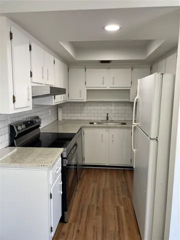 a kitchen with a white cabinets and wooden floor