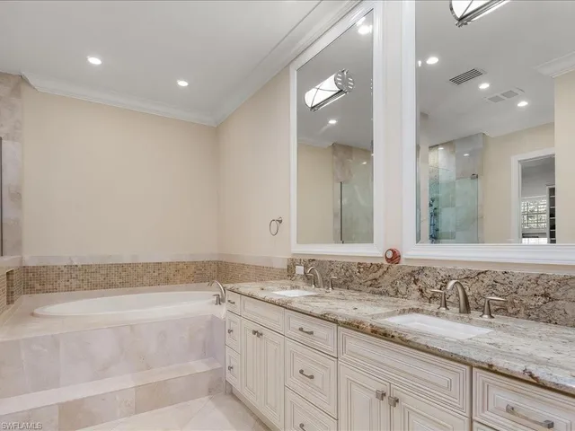 a bathroom with a granite countertop double vanity sink and bathtub