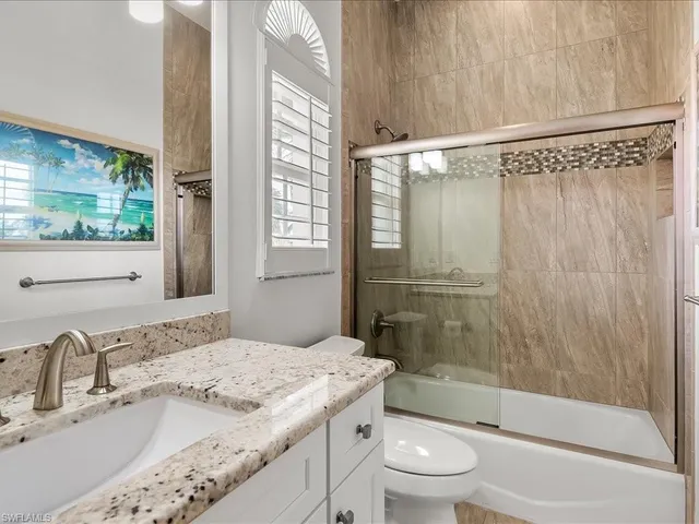 a bathroom with a granite countertop sink a toilet and shower