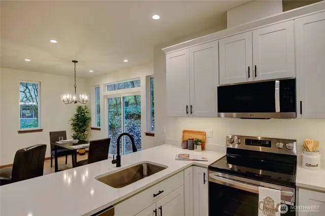 a kitchen with stainless steel appliances kitchen island granite countertop a stove a refrigerator and a dining table with wooden floor