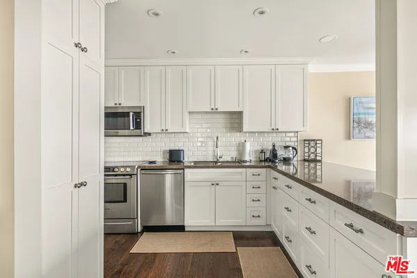 a kitchen with granite countertop white cabinets and white appliances