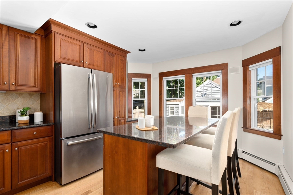 15 Laird Road Medford, MA 02155 - Photo 11 of 42 a kitchen with stainless steel appliances granite countertop a refrigerator a stove and a dining table with wooden cabinet