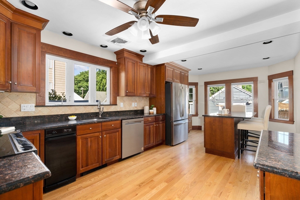 15 Laird Road Medford, MA 02155 - Photo 10 of 42 a kitchen with stainless steel appliances granite countertop a refrigerator a sink dishwasher a stove and a dining table with wooden floor