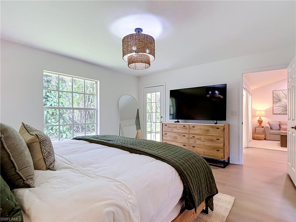 812 102nd Avenue North Naples, FL 34108 - Photo 19 of 33 Light-toned wood-finish flooring, white walls, and a two-tiered woven pendant light fixture