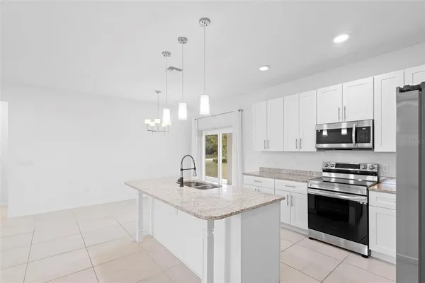 a kitchen with stainless steel appliances granite countertop a sink stove oven and white cabinets