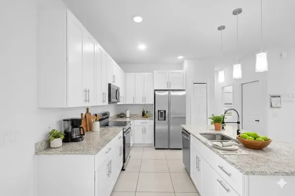 a kitchen with stainless steel appliances granite countertop a sink a stove a refrigerator a washer and cabinets