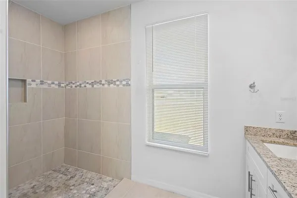 a bathroom with a granite countertop sink a shower and a window