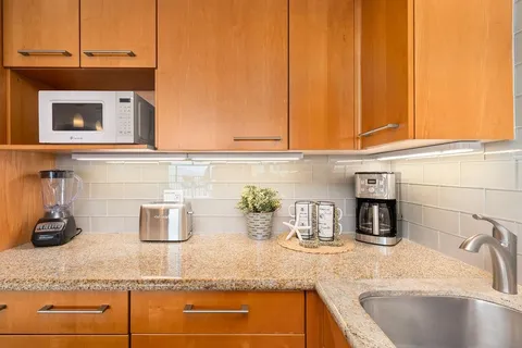 a kitchen with stainless steel appliances granite countertop a sink a stove and a wooden cabinets