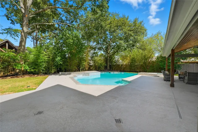 a view of a swimming pool with a yard and large trees