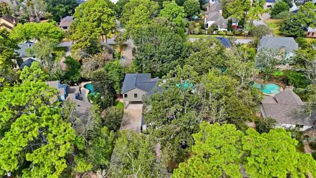 an aerial view of residential house with outdoor space and trees all around