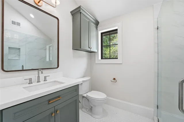 a bathroom with a toilet a sink a mirror and a shower