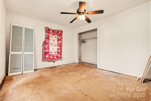 an empty room with windows and fan