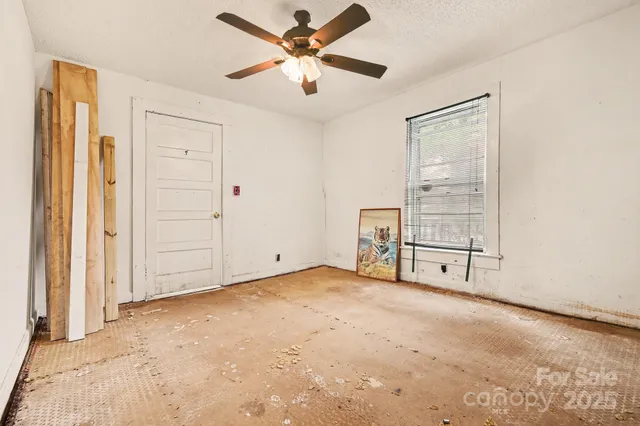 an empty room with windows and ceiling fan
