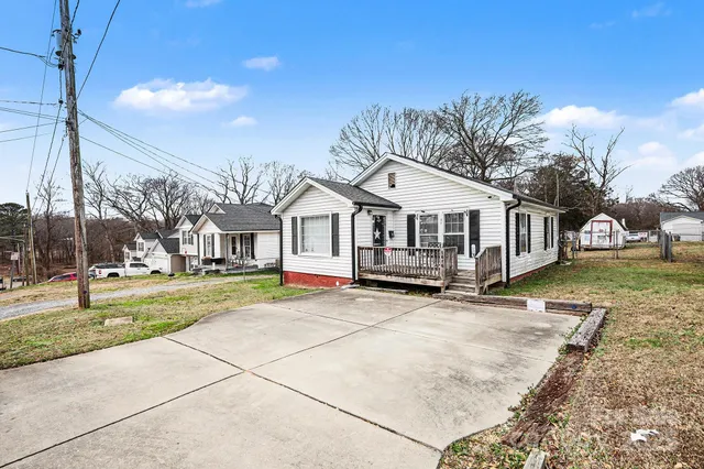 a view of a white house with a big yard and large trees