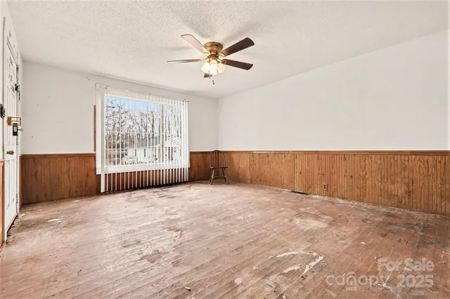 an empty room with windows and fan