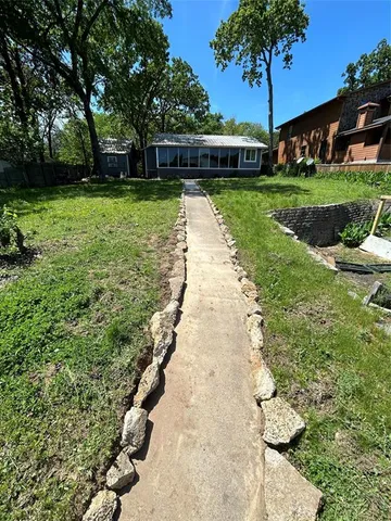 a view of a backyard with potted plants and large trees