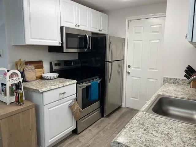 a kitchen with granite countertop a sink stove and refrigerator