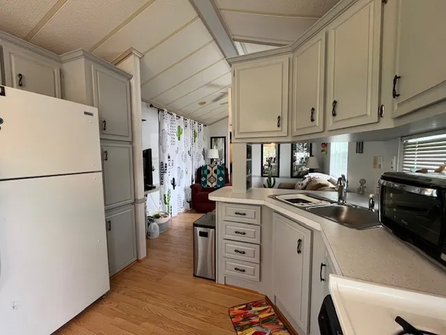 a kitchen with a refrigerator a stove cabinets and living room view