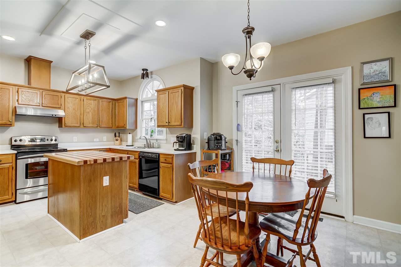 5121 Celbridge Place Raleigh, NC 27613 - Photo 7 of 22 a kitchen with stainless steel appliances granite countertop a stove top oven a sink a dining table and chairs with wooden floor