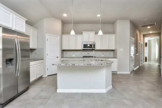 a kitchen with kitchen island granite countertop a sink cabinets and stainless steel appliances