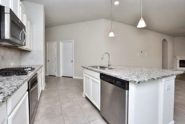 a kitchen with granite countertop a sink stainless steel appliances and white cabinets