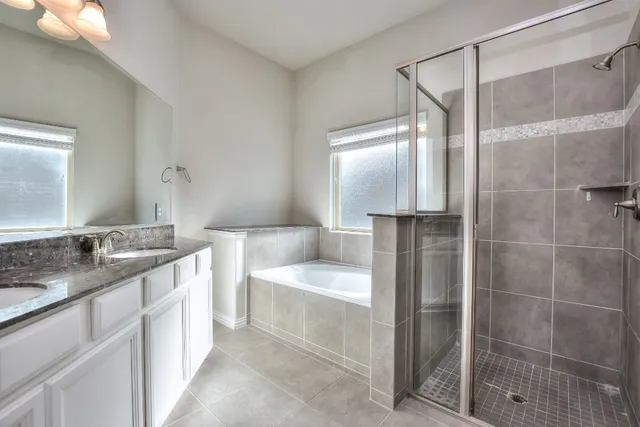 a bathroom with a granite countertop bathtub a double vanity sink and mirror