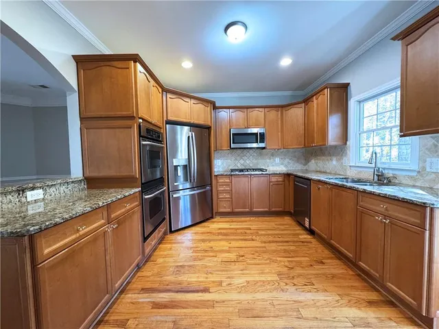a large kitchen with stainless steel appliances granite countertop a sink counter space cabinets and a large window
