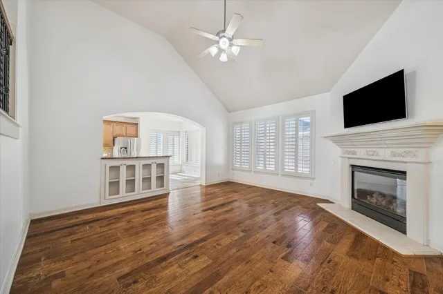 a view of an empty room with wooden floor fireplace and a window