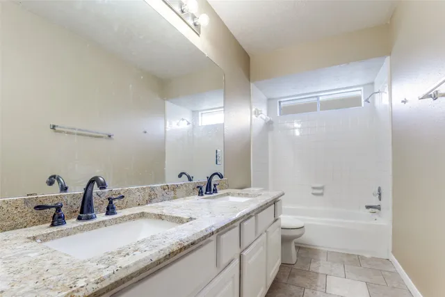 a bathroom with a granite countertop sink mirror toilet and bathtub
