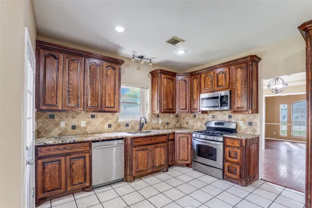 a kitchen with stainless steel appliances granite countertop a sink stove refrigerator and cabinets