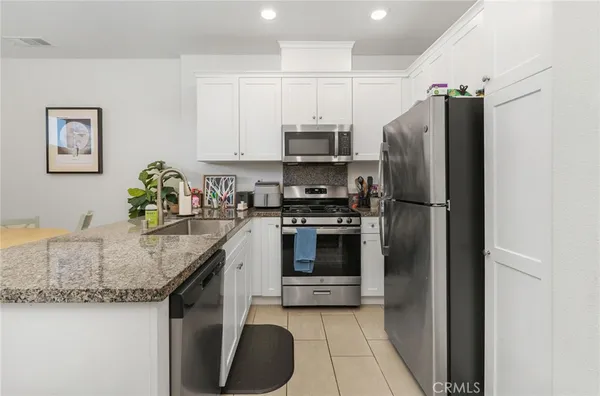 a kitchen with granite countertop a refrigerator and a stove top oven