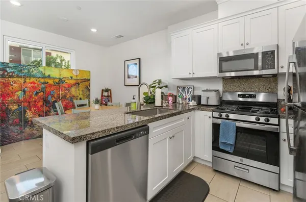a kitchen with stainless steel appliances granite countertop a stove a sink and a microwave