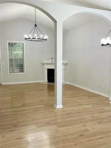 a view of an empty room with wooden floor and chandelier